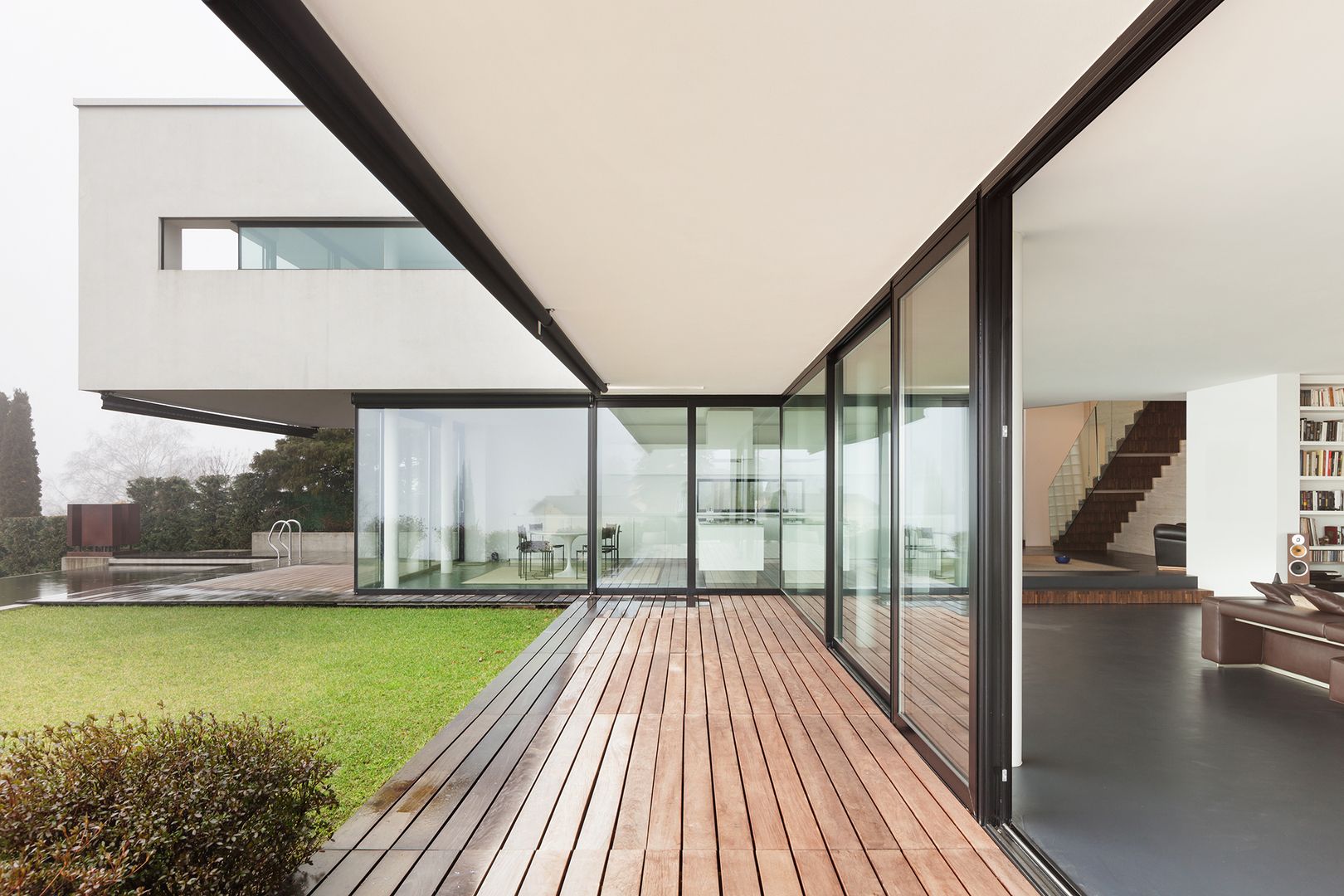 Modernes Gebäude mit großflächigen Glaswänden, Holzdeck und überstehendem Dach